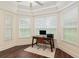 Bright home office featuring hardwood floors, a tray ceiling, three large windows and a modern desk setup at 3883 Se 51St Ct, Ocala, FL 34480