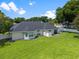 Back exterior view of home with a large green lawn and a screened lanai at 3883 Se 51St Ct, Ocala, FL 34480