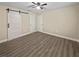 Spacious bedroom featuring a sliding barn door, ceiling fan, and stylish wood-look flooring at 5 Bahia Circle Pl, Ocala, FL 34472