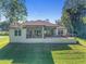 Back exterior showcasing a covered patio with plenty of seating, and a well-maintained yard at 5034 Nw 75Th Ave, Ocala, FL 34482