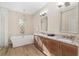 Bright bathroom featuring a modern soaking tub, dual sinks, and wood-look tile floors at 5034 Nw 75Th Ave, Ocala, FL 34482