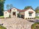 Elegant stucco home featuring a stone facade, paved driveway, and manicured landscaping at 5034 Nw 75Th Ave, Ocala, FL 34482