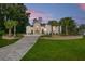 Elegant stucco home featuring a stone facade, paved driveway, and a meticulously landscaped front yard with palm trees at 5034 Nw 75Th Ave, Ocala, FL 34482