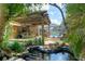 Backyard pond with waterfall feature, pergola, and screened-in pool at 5390 Se 15Th Ct, Ocala, FL 34480