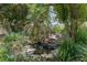 Backyard pond with waterfall feature surrounded by lush greenery and trees, creating a serene outdoor space at 5390 Se 15Th Ct, Ocala, FL 34480