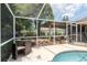 Screened in lanai area with a table and chairs for entertainment by the gorgeous backyard pool at 5390 Se 15Th Ct, Ocala, FL 34480