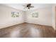 Bright, vacant bedroom featuring hardwood floors, natural light from dual windows, and a ceiling fan at 6495 Sw 109Th St, Ocala, FL 34476