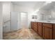 Bathroom with double sinks, wood cabinets, decorative lighting, and access to walk-in closet at 8640 Sw 83Rd Loop, Ocala, FL 34481