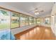 Sunroom with a ceiling fan, hardwood floors, neutral walls, and a view of the outdoors through the many windows at 8704 Sw 94Th Ln # G, Ocala, FL 34481