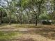 Lush property with a canopy of mature trees shading a well-maintained lawn, house and swing set visible at 9805 Se 182Nd Avenue Rd, Ocklawaha, FL 32179