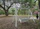 Relaxing backyard featuring a classic white swing set amidst mature trees and lush landscaping at 9805 Se 182Nd Avenue Rd, Ocklawaha, FL 32179
