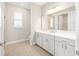 Bright bathroom with white cabinets, quartz counters, tile floor, and large mirror at 10008 Sw 85Th Place Rd, Ocala, FL 34481