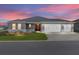 Beautiful single-story home featuring a three-car garage, well-manicured lawn, and paver driveway under a colorful sunset at 10008 Sw 85Th Place Rd, Ocala, FL 34481