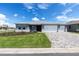 Inviting one-story home showcasing a three-car garage and paver driveway, accented by lush landscaping and a blue sky at 10008 Sw 85Th Place Rd, Ocala, FL 34481