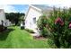 Landscaped side yard, featuring green grass and flowering shrubs, complements this home's serene outdoor space at 11470 Sw 139Th St, Dunnellon, FL 34432