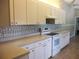 Well-lit kitchen featuring white cabinets, an electric range, and tiled backsplash, enhancing the cooking experience at 11470 Sw 139Th St, Dunnellon, FL 34432