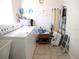 Well-lit laundry room featuring tile flooring, a large washing machine and dryer, and ample storage for cleaning supplies at 11470 Sw 139Th St, Dunnellon, FL 34432