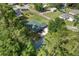 An aerial view of a well-maintained home surrounded by lush greenery, a large driveway, and a quaint shed at 12681 Se 54Th Ave, Belleview, FL 34420
