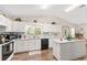 Bright kitchen featuring white cabinetry, a large window, an island and modern appliances at 12681 Se 54Th Ave, Belleview, FL 34420