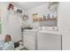Functional laundry room with washer, dryer, and shelving providing ample storage space at 12681 Se 54Th Ave, Belleview, FL 34420
