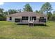Well maintained backyard with a large deck, green grass, and a view of the home's exterior at 13741 Sw 73Rd St, Ocala, FL 34481