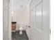 Bathroom with a toilet, cabinet sink, black and grey patterned tile, and a bright white door at 13741 Sw 73Rd St, Ocala, FL 34481