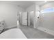 Bright bathroom showcasing a modern soaking tub, walk-in shower, tiled floors, and white vanity with black hardware at 13780 Sw 42Nd Court Rd, Ocala, FL 34473