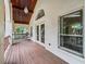 Charming balcony with wooden flooring, white columns, and a decorative arched window overlooking lush greenery at 1630 Se 29Th Ter, Ocala, FL 34471