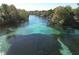 Aerial view of a river, showing clear turquoise water surrounded by lush greenery and trees at 19424 Sw 77Th Loop, Dunnellon, FL 34432