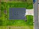 Aerial view of home featuring a well-manicured lawn, driveway, garden, and modern roof design at 19424 Sw 77Th Loop, Dunnellon, FL 34432