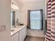 Bright bathroom with a long vanity, ample counter space, a large mirror, and a gray and white striped shower curtain at 19424 Sw 77Th Loop, Dunnellon, FL 34432