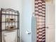 Bathroom featuring a toilet with a rack of storage baskets and a striped shower curtain by a partially visible white door at 19424 Sw 77Th Loop, Dunnellon, FL 34432