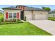 A well-kept home featuring a lush lawn, red accents, and a spacious two-car garage at 19424 Sw 77Th Loop, Dunnellon, FL 34432