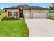 Inviting home with bright red shutters, a well-maintained lawn, and a two-car garage at 19424 Sw 77Th Loop, Dunnellon, FL 34432