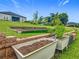 Backyard featuring garden area with raised beds and container plants, set against a backdrop of lush greenery and house at 19424 Sw 77Th Loop, Dunnellon, FL 34432