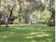 View of green backyard with a shed and trailer with an expansive lawn and mature trees at 2131 Ne 145Th Avenue Rd, Silver Springs, FL 34488