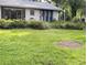 View of home exterior featuring green yard with plants, an outdoor table and sliding glass doors at 2131 Ne 145Th Avenue Rd, Silver Springs, FL 34488