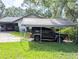 Single-Gathering home featuring a carport and a garage, surrounded by green lawn and mature trees at 2131 Ne 145Th Avenue Rd, Silver Springs, FL 34488