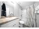 Well-lit bathroom with gray-toned flooring, a neutral vanity, and a shower with patterned curtain at 3094 Se 144Th Pl, Summerfield, FL 34491