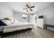 Bedroom showcasing neutral walls and gray wood flooring, ceiling fan, complemented by a large window and dresser at 3094 Se 144Th Pl, Summerfield, FL 34491