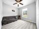 Bright bedroom with a ceiling fan, gray wood floors, a sofa, and a window with natural light at 3094 Se 144Th Pl, Summerfield, FL 34491