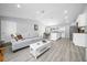 Bright open-concept living room with a comfortable sofa, modern coffee table, and light gray wood-look flooring at 3094 Se 144Th Pl, Summerfield, FL 34491