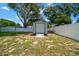 Backyard storage shed with a white fence and ramp, offering practical storage solutions for outdoor equipment and tools at 3094 Se 144Th Pl, Summerfield, FL 34491