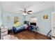 Light blue bedroom featuring wood floors, ceiling fan, and two windows with a workstation at 3428 Ne 17Th Ter, Ocala, FL 34479