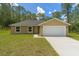 Charming single-story home featuring a two-car garage, a well-maintained lawn, and a tree-lined backdrop at 391 Nw Crocus Ln, Dunnellon, FL 34431