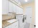 Bright laundry room featuring modern washer and dryer, granite countertops, and ample cabinet space at 5024 Sw 114Th Street Rd, Ocala, FL 34476