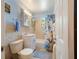 Bright bathroom with a light blue painted wall, mirrored medicine cabinet, and tub-shower with floral shower curtain at 5915 Se Holly Rd, Belleview, FL 34420