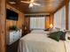 Cozy bedroom with wood paneling, ceiling fan, and two twin beds at 5915 Se Holly Rd, Belleview, FL 34420