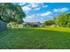 Wide backyard with manicured lawn, mature trees, fence, and home exterior at 6142 Se 37Th Ter, Ocala, FL 34480