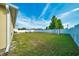 Large, fenced backyard with lush green grass, seating area, and mature shade tree at 7327 Sw 129Th Ln, Ocala, FL 34473